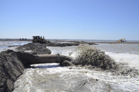 Dredged sediment pumping out of a pipe to help build coastal ecosystems.