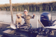 A boy and his dog out recreating on a boat in a marsh in Louisiana.