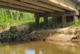 a line is dropped into brown water from a bridge