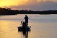 a silhouette of a man fishing off of a boat is shown