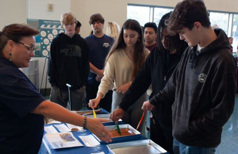 a group of students hold different colored sticks into silver pans