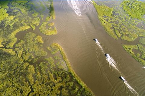 Aerial view of boats traveling along channels surrounded by marsh in Louisiana.